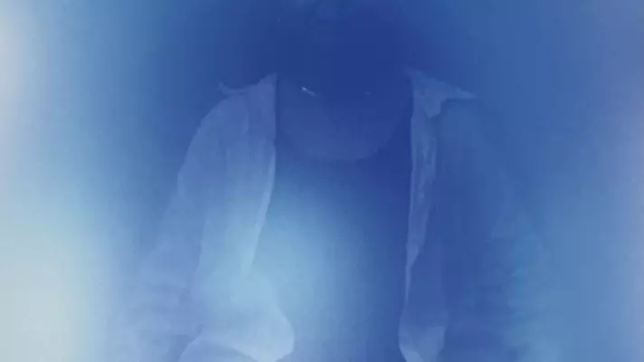 A seated person in blue light.