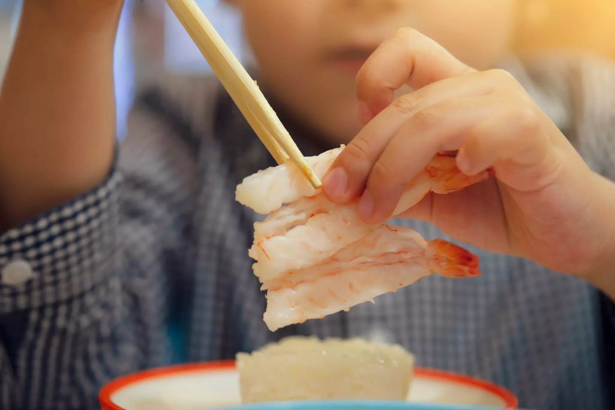 Young boy eating sushi with chopsticks