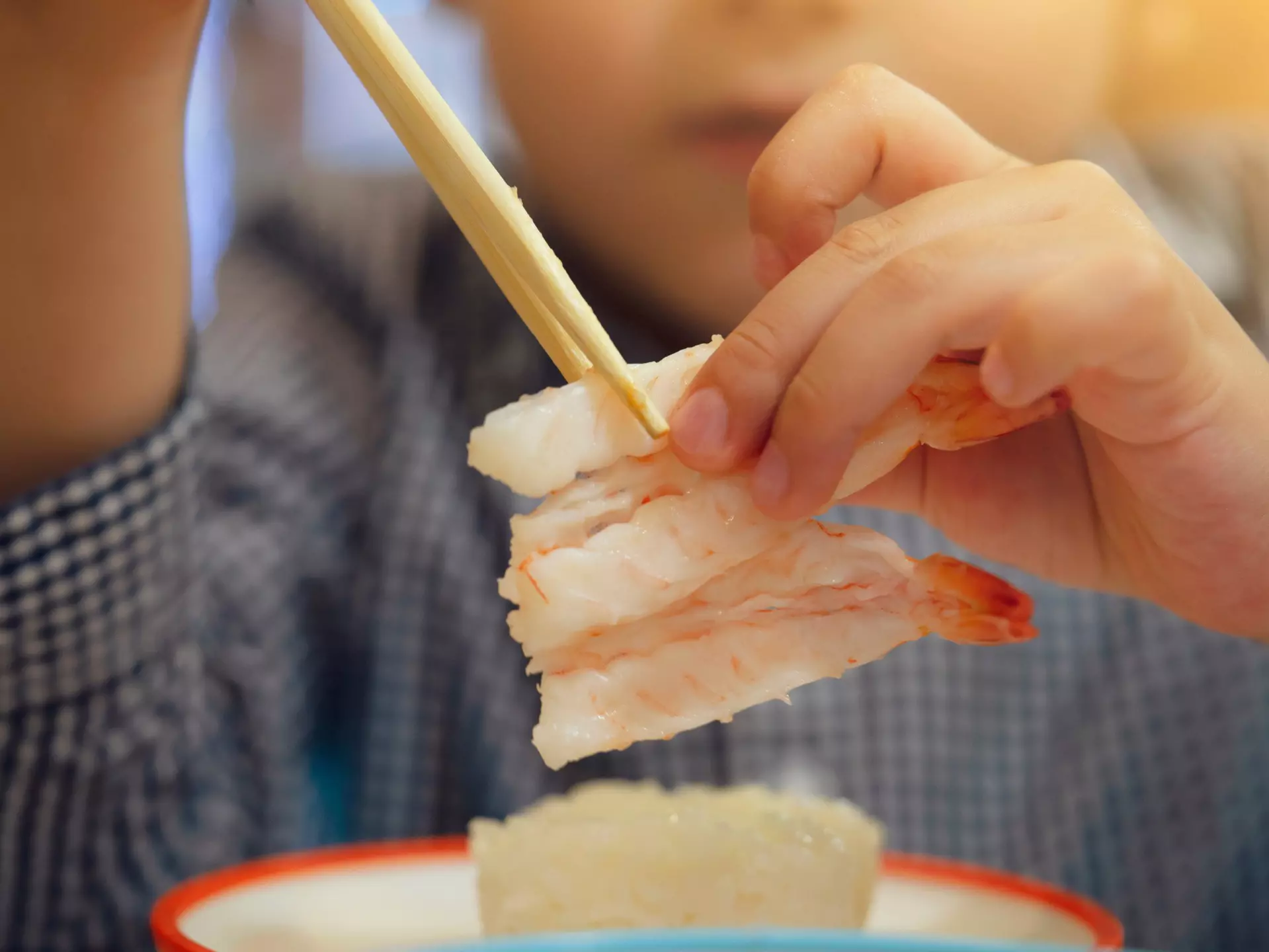 Young boy eating sushi with chopsticks