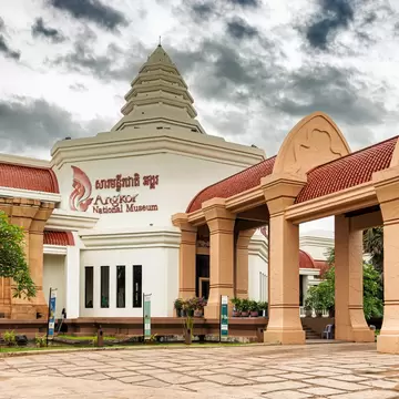 The entrance to a large museum building under gray clouds.