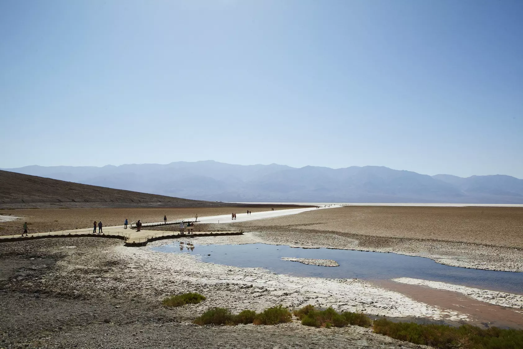 People exploring trails and raised boardwalks at Badwater.