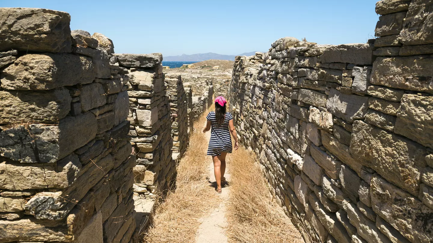 A woman walks amidst the ancient ruins on Delos near Mykonos in Greece.