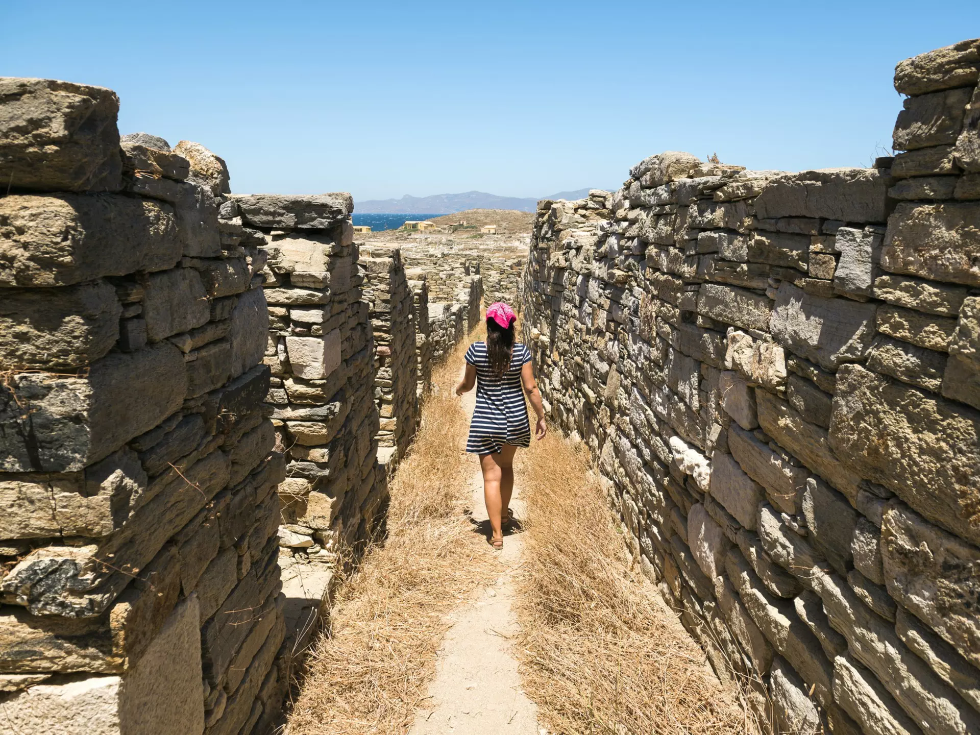 A woman walks amidst the ancient ruins on Delos near Mykonos in Greece.