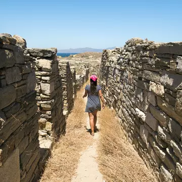 A woman walks amidst the ancient ruins on Delos near Mykonos in Greece.