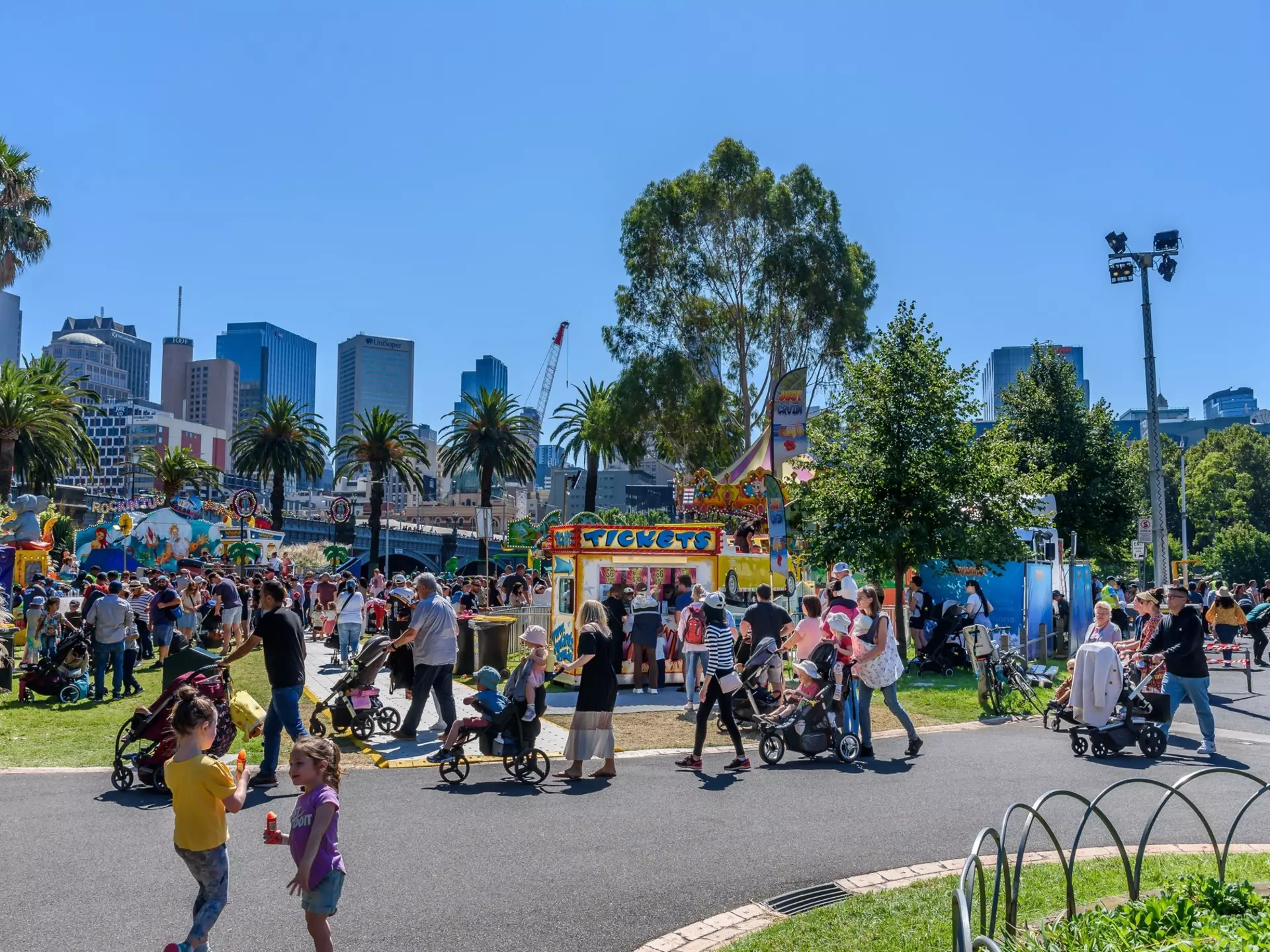 Melbourne, Victoria, Australia, March 12th, 2022: Parents and children line up to buy tickets for rides at the Moomba Carnival on the banks of the Yarra River with the city buildings in the background, License Type: media, Download Time: 2025-12-02T09:31:48.000Z, User: sashabrady26, Editorial: true, purchase_order: 65050 - Digital Destinations and Articles, job: Lonely Planet, client: Best things to do in Melbourne with kids, other: Sasha Brady