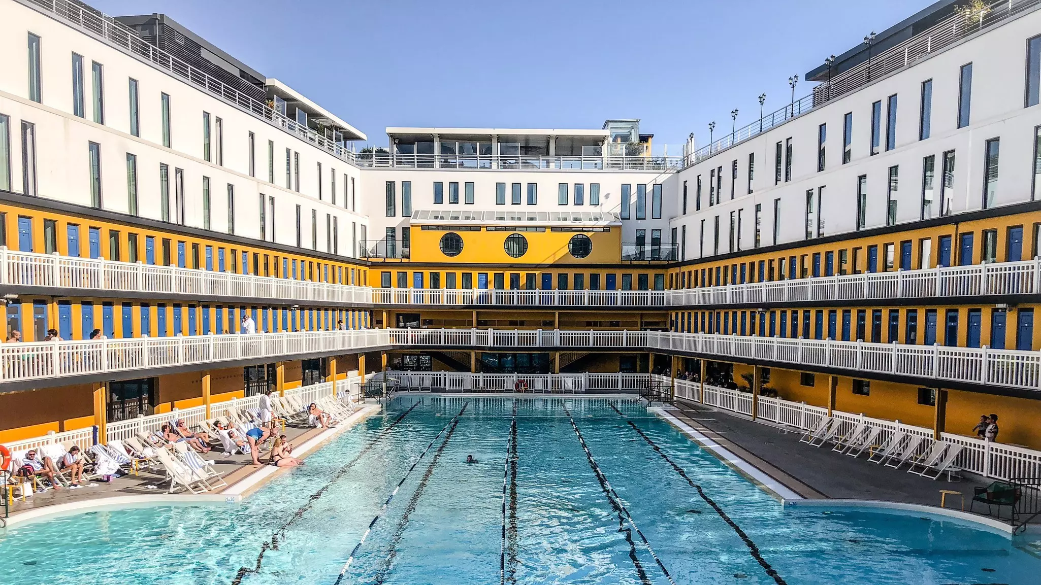 An outdoor swimming pool surrounded by the walls of a luxury hotel.