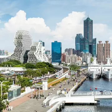 Skyline with various landmark geometrically shaped buildings and boats in the harbor at Kaohsiung, Taiwan.