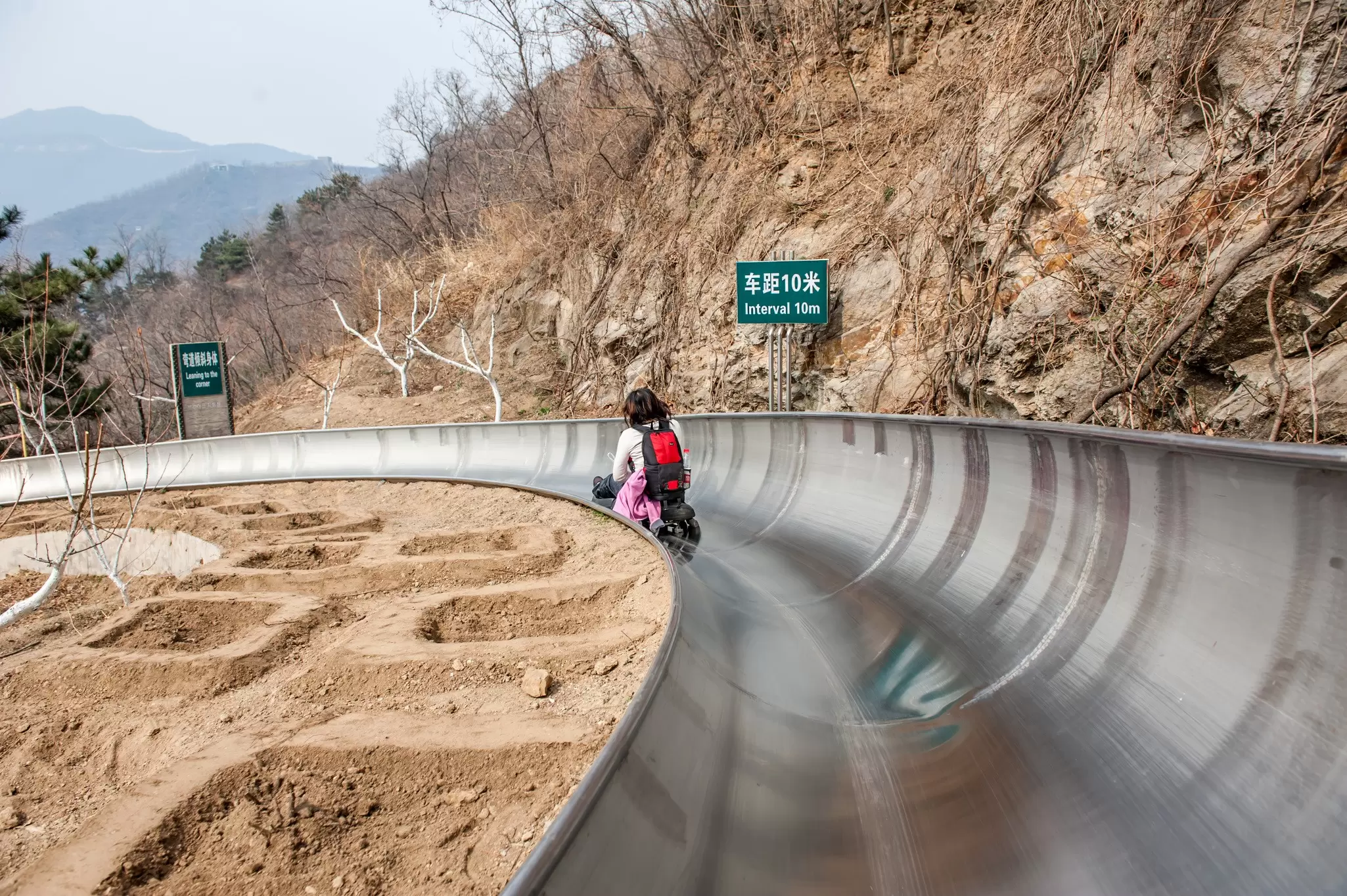 Woman rides a toboggan slide near the Mutianyu section of the Great Wall of China.