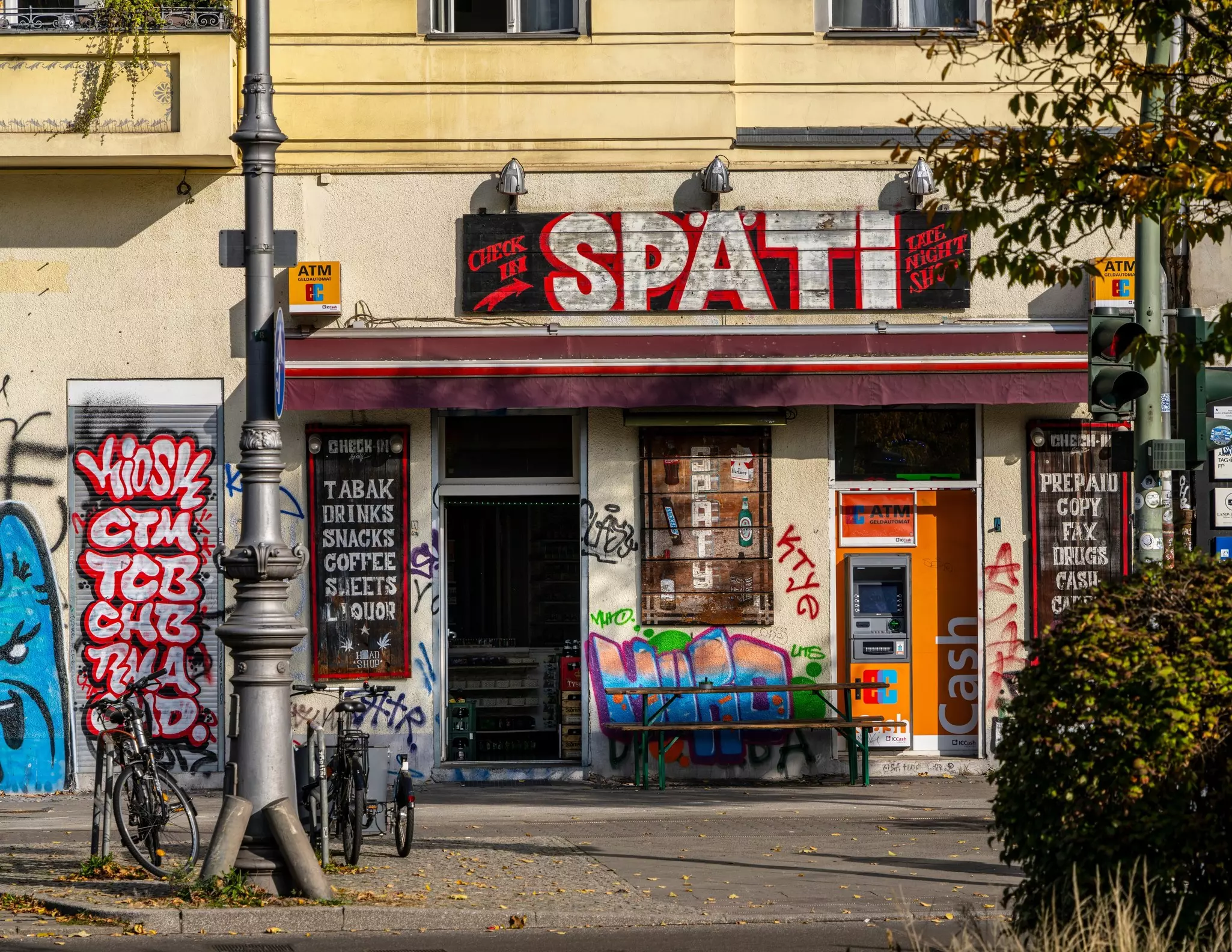 A small store with graffiti outside and signs indicating it sells drinks and snacks