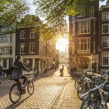 People ride bicycles silhouetted by the early morning sun in Amsterdam