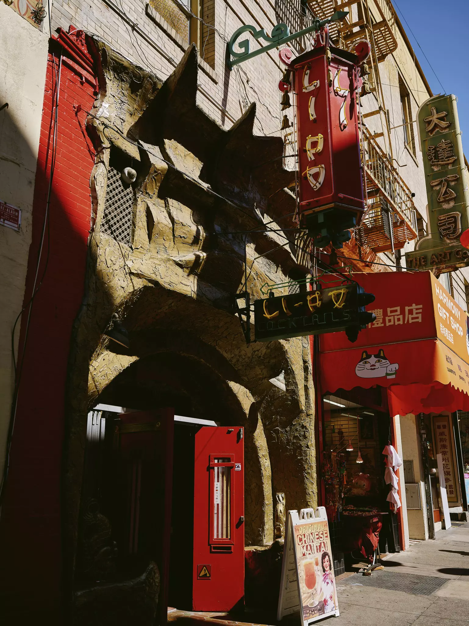 The facade of a lounge with a long, narrow red door. The neon sign above the door says "Li-Po Cocktails," and another neon sign above it says "Lipo."