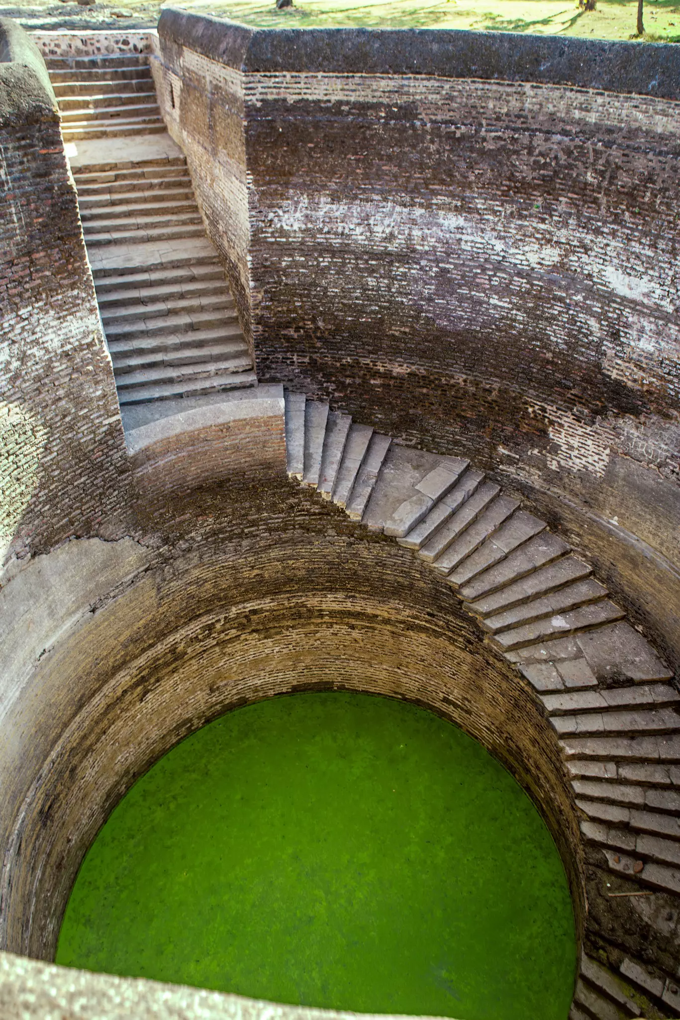 A spiral staircase leads down to a well filled with water