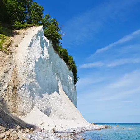 A white, chalky cliff overlooking the sea on a sunny day.