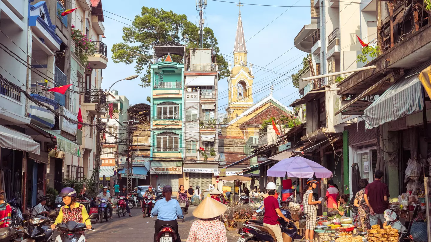 A picturesque street of Cholon buzzing with market activity, a view of townhouses and Cha Tam Church (St. Francis Xavier Parish Church).