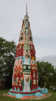 An art work in the shape of a totem pole is displayed on a grass lawn.