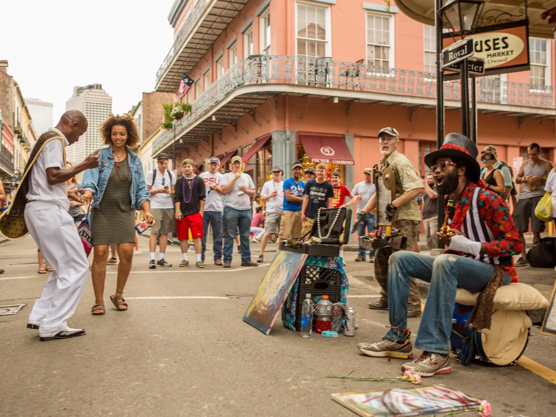 A two-man band plays on a corner in the French Quarter in New Orleans, with people dancing in the street.