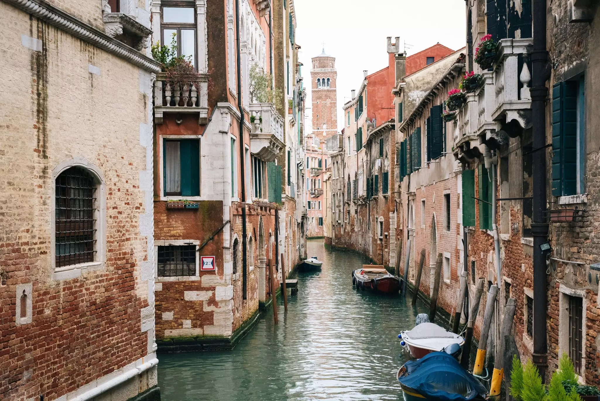 Small boats in a narrow canal lined with buildings.