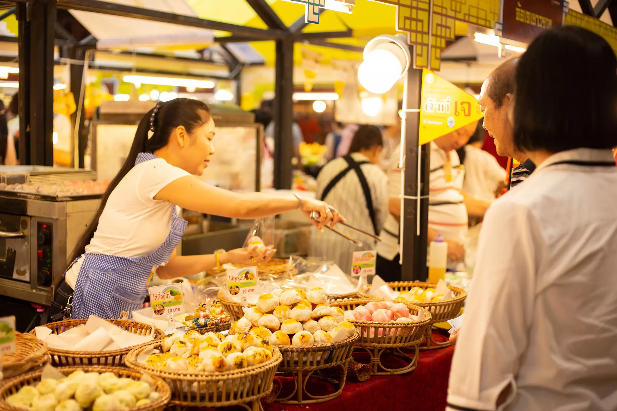 A woman picks up dumplings displayed in baskets at a stall at a food festival.