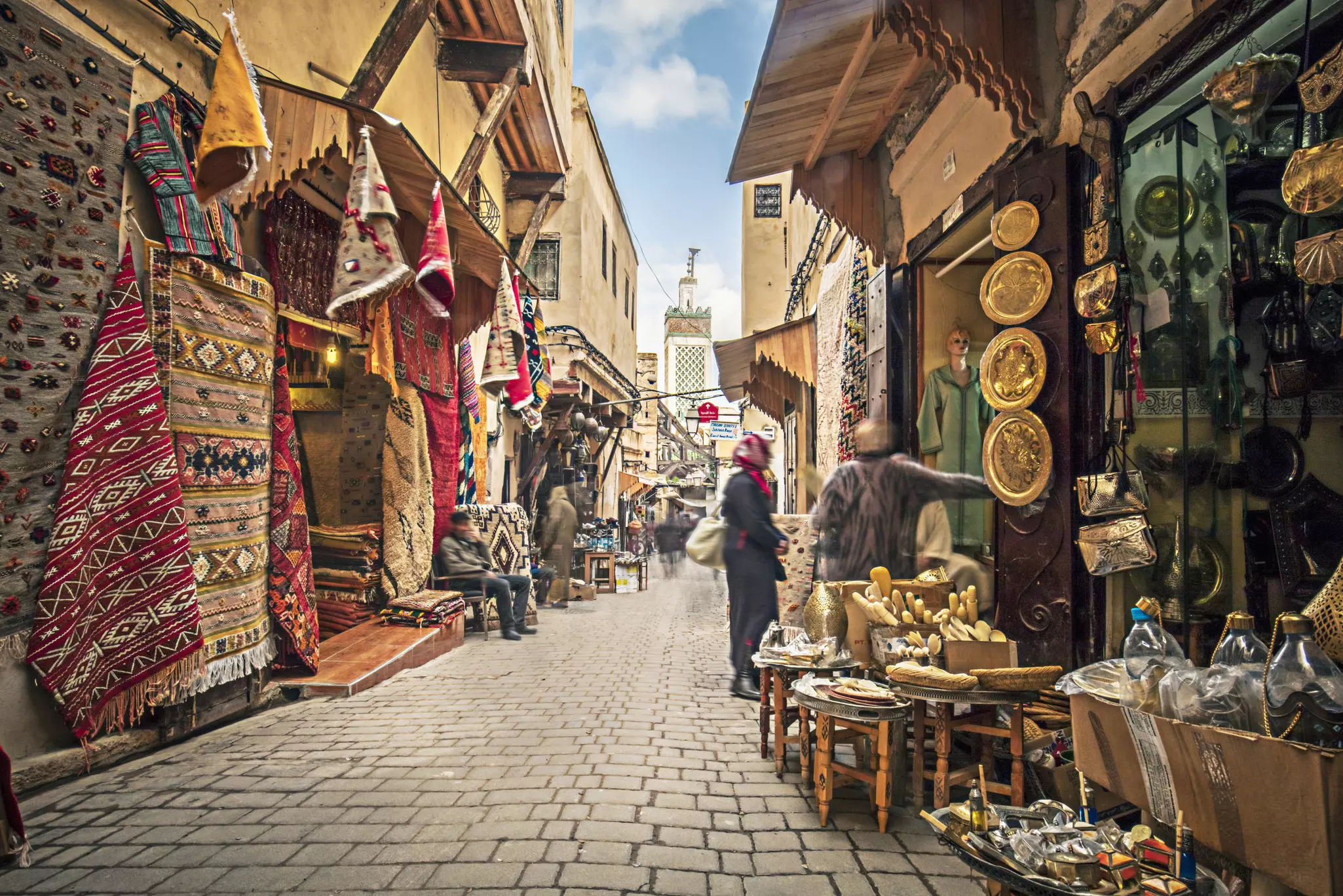 A cobbled street lined with stalls selling rugs, gold lamps and plates.