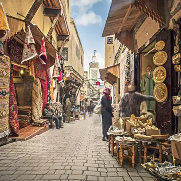 A cobbled street lined with stalls selling rugs, gold lamps and plates.