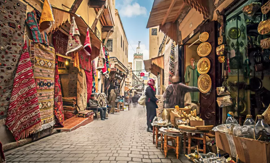 A cobbled street lined with stalls selling rugs, gold lamps and plates.