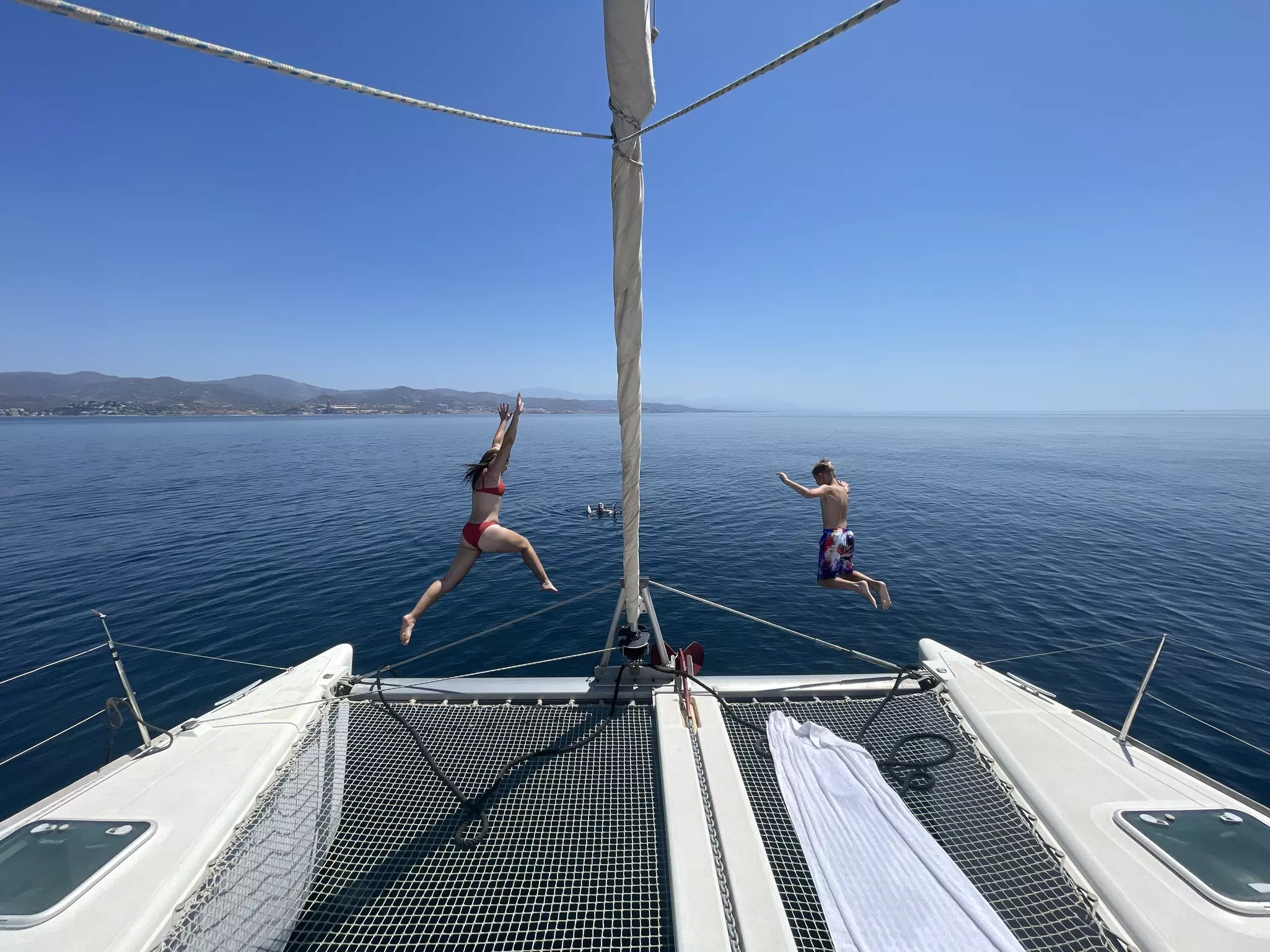 A boy and girl jump into the ocean off of the back of a sail boat. IMG0383.jpeg