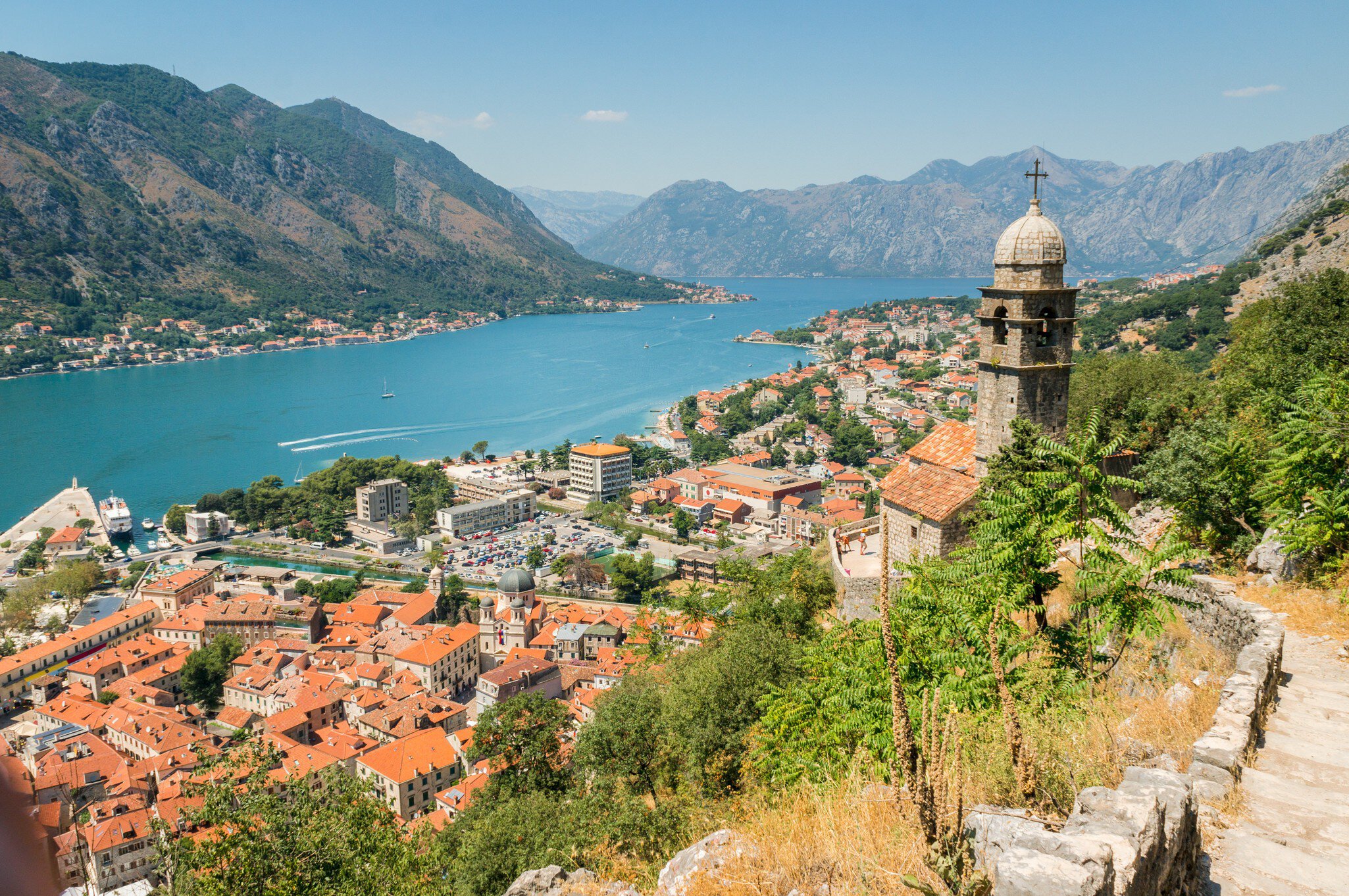 City walls and steps lead up to a view over a lakeside city.