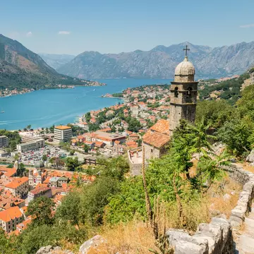 City walls and steps lead up to a view over a lakeside city.