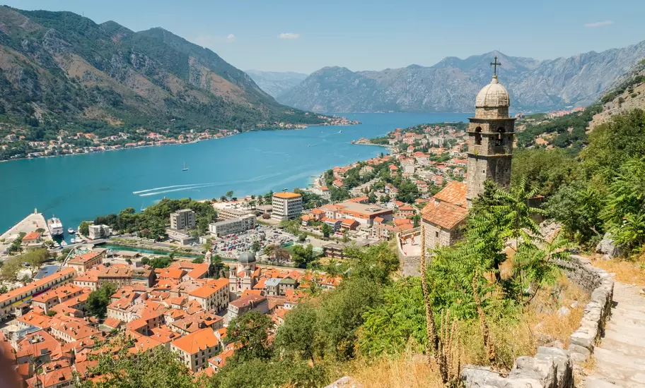 City walls and steps lead up to a view over a lakeside city.