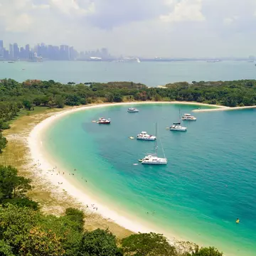 Aerial picture of the beach of Lazarus Island with yachts moored in the cove and the city visible in the distance, Singapore