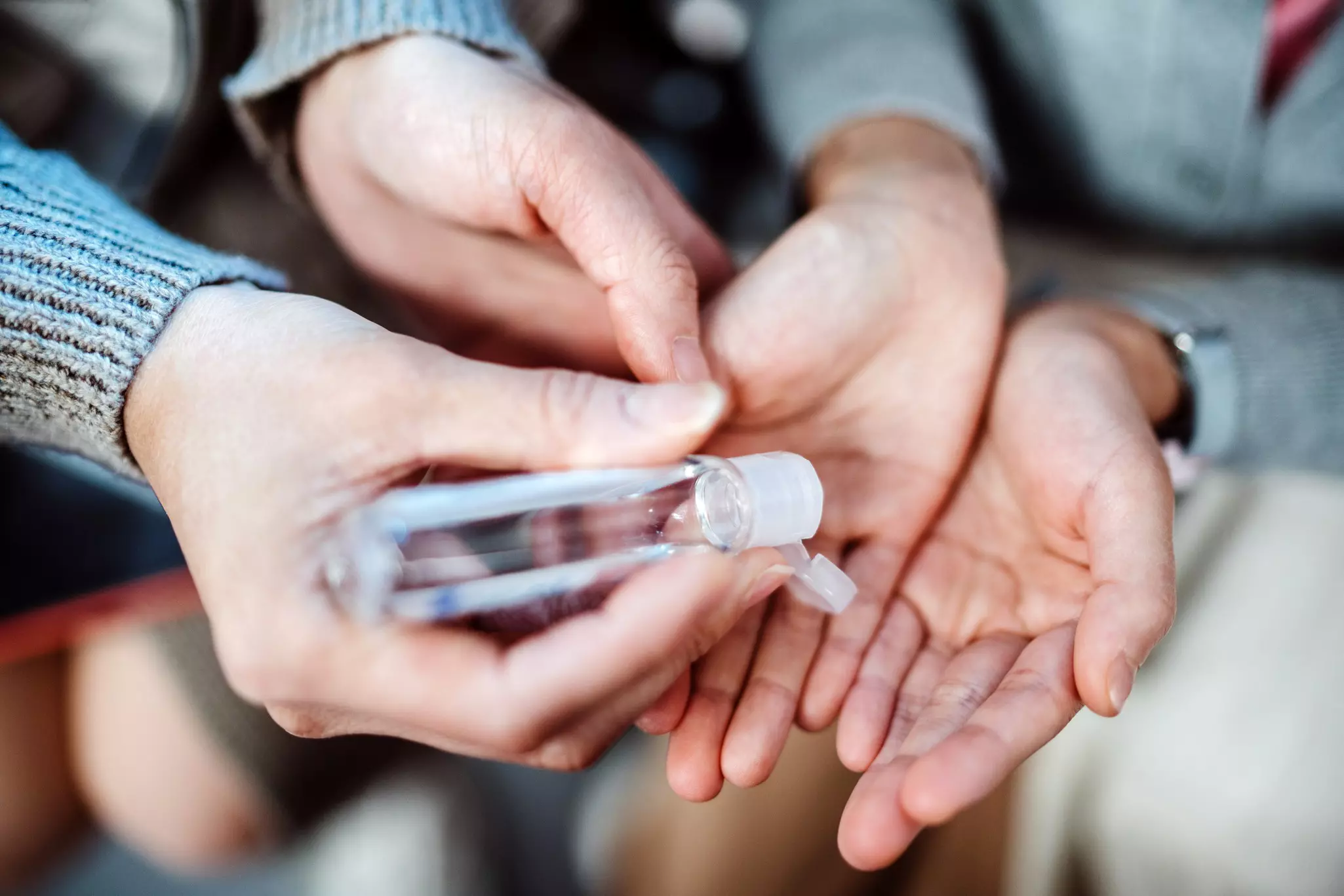 Mom squeezing hand sanitizer onto her daughter’s hands.