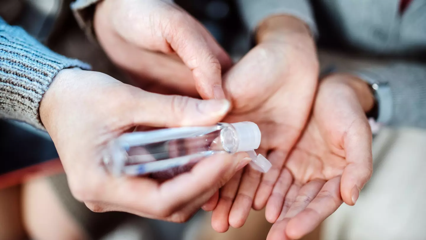 Mom squeezing hand sanitizer onto her daughter’s hands.