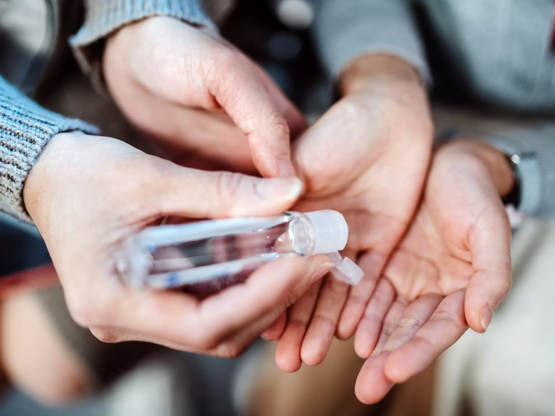 Mom squeezing hand sanitizer onto her daughter’s hands.