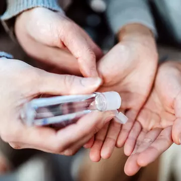 Mom squeezing hand sanitizer onto her daughter’s hands.