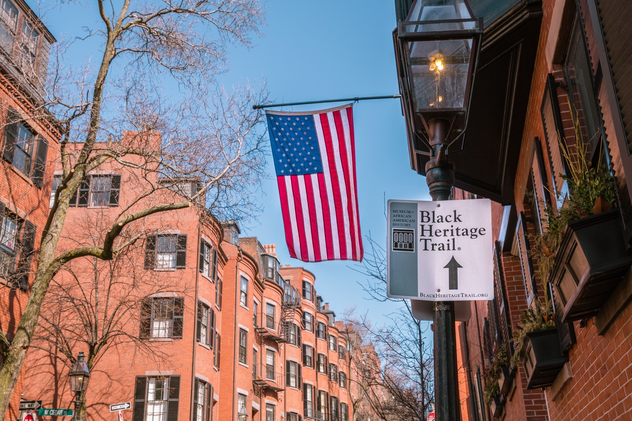 Boston, MA, US-June 10, 2023: Black Heritage Trail sign in Boston's historic Beacon Hill nieghborhood with American flag and 19th century brick buildings in background., License Type: media, Download Time: 2024-09-10T06:43:40.000Z, User: oneseven7891, Editorial: true, purchase_order: 56530, job: Global Publishing WIP, client: Pocket Boston 6, other: Dominic Allen