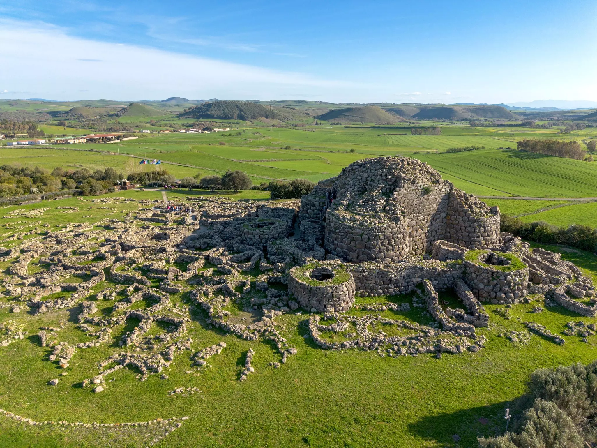 Aerial view of ancient ruins made of stone amid green grass on a sunny day.