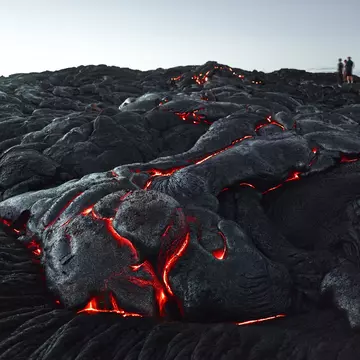 Visitors standing on a glowing lava field in Hawaii Volcanoes National Park