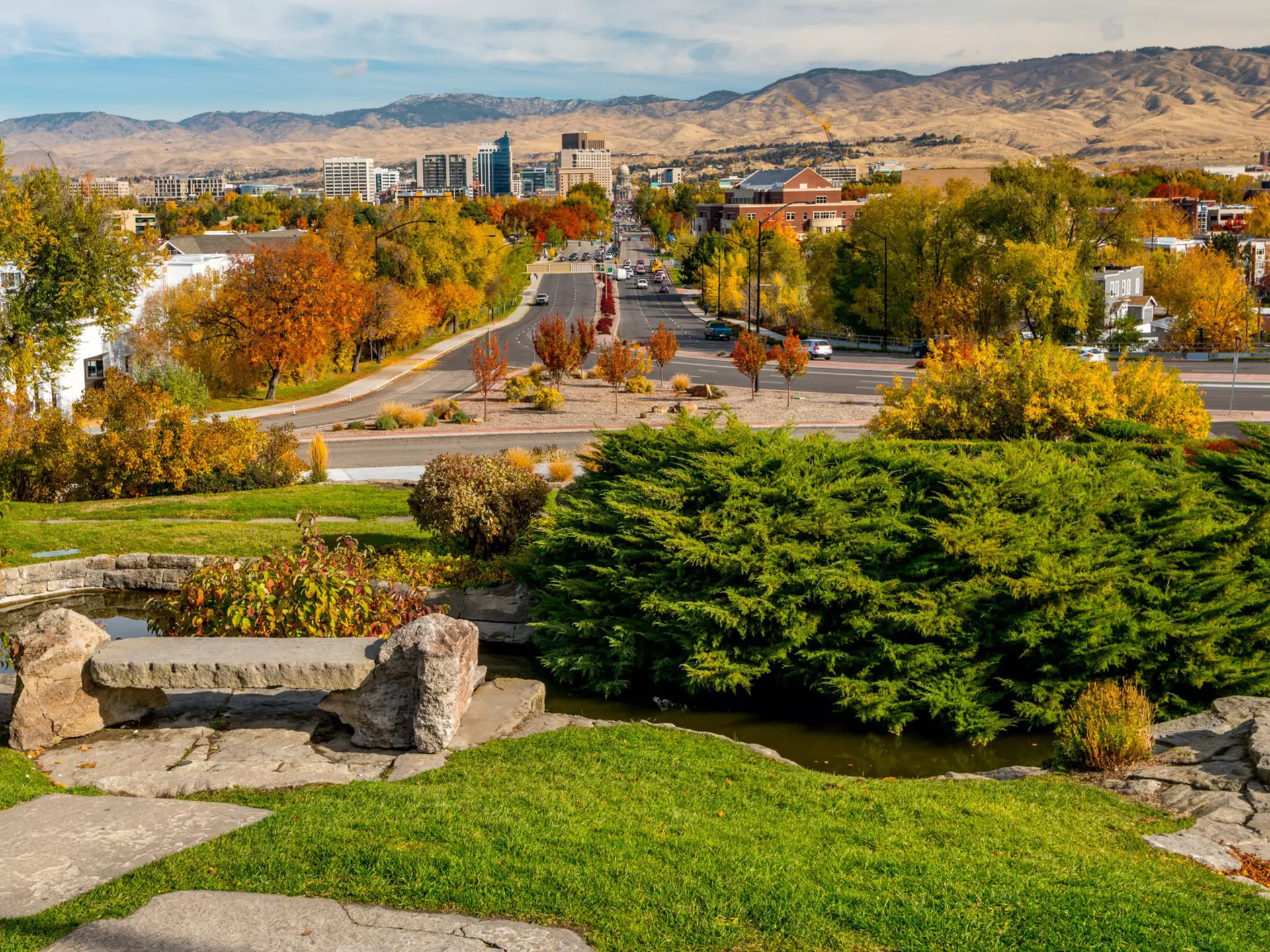 Fall trees with autumn colours line the streets of a low-rise city in a mountainous region