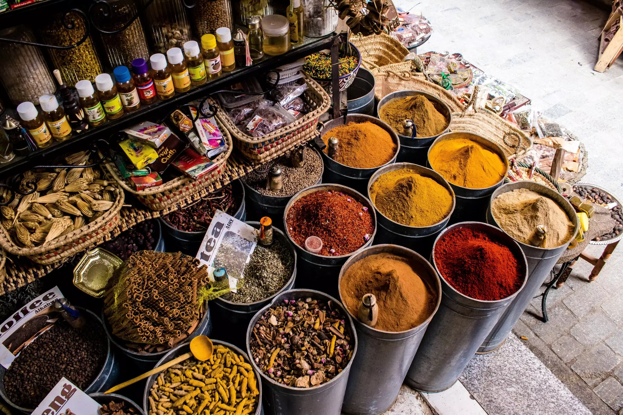 Tall bins of colored spices on the ground.