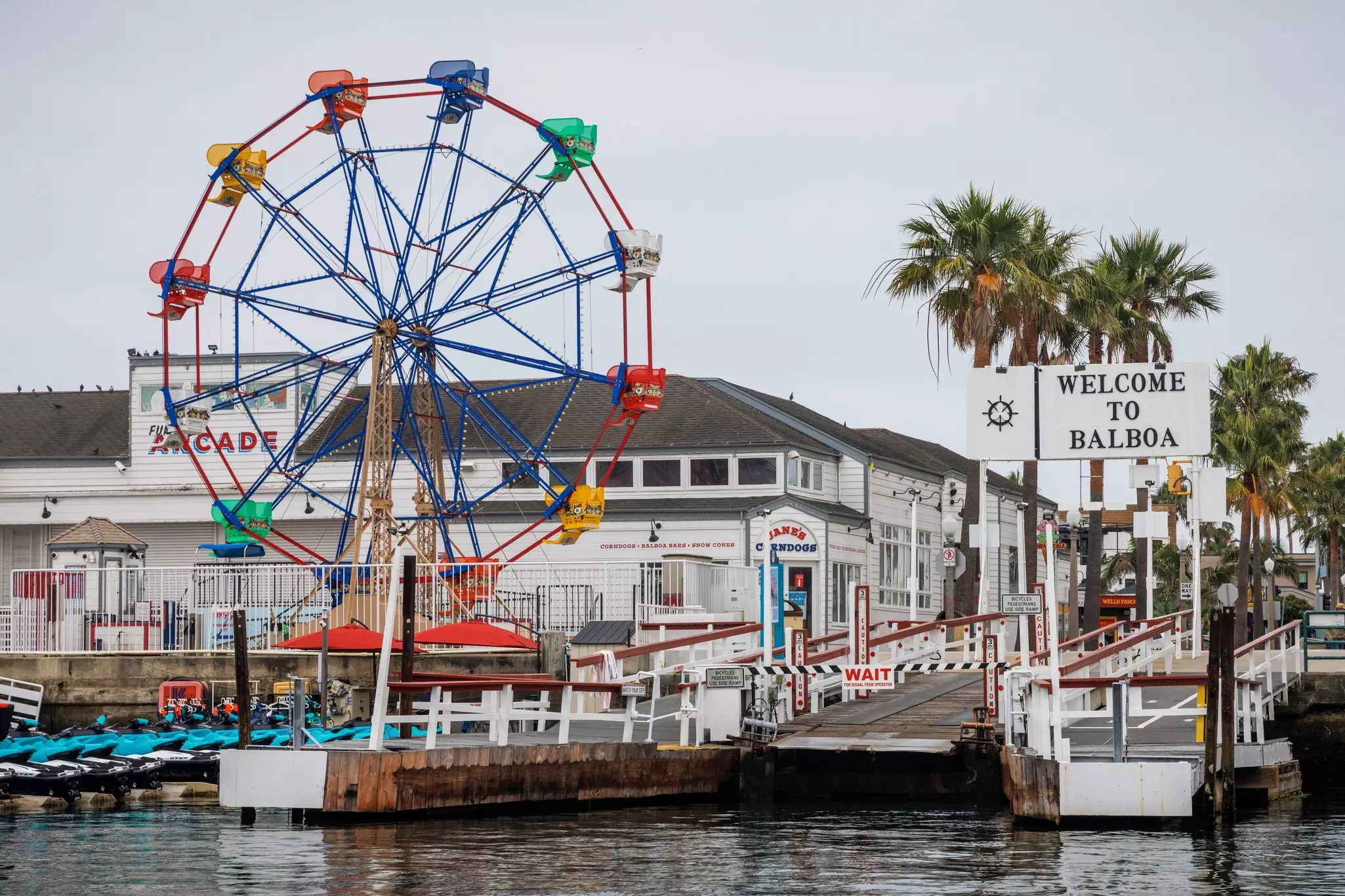 Image of ferris wheel bordering the sea with a sign reading "Welcome to Balboa" on the right.