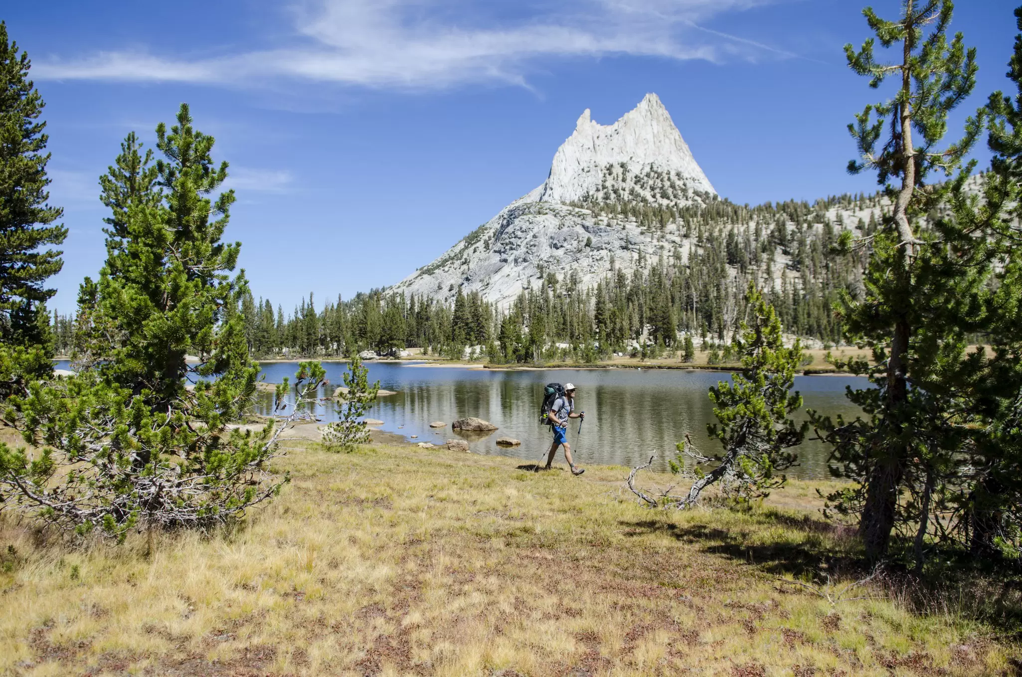 A young man walks past Cathedral Lake during a 27.3 mile backpacking trip from Tuolumne Meadows to Yosemite Valley, California.