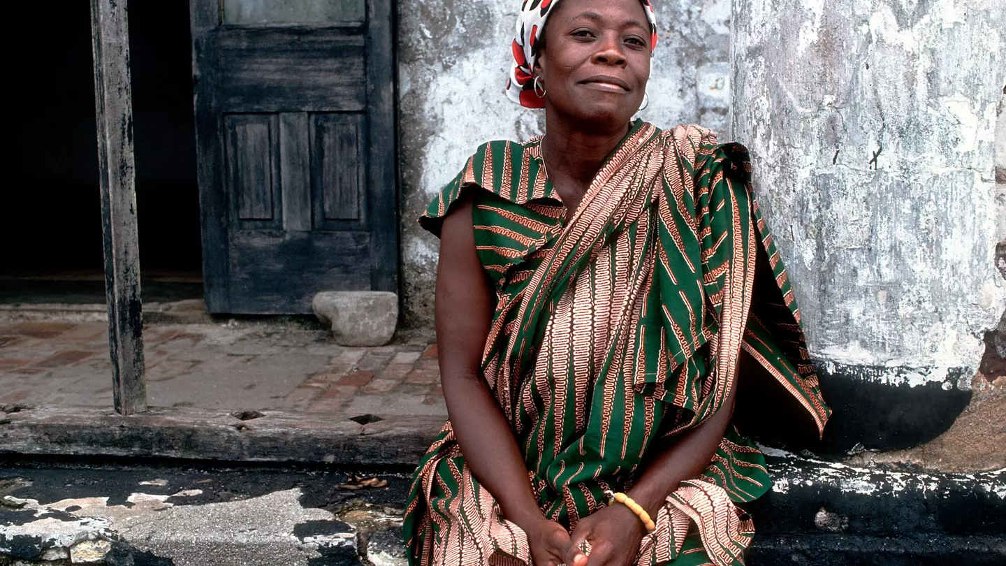 A Ghanaian woman poses for a photo close to Elmina Castle in Ghana.