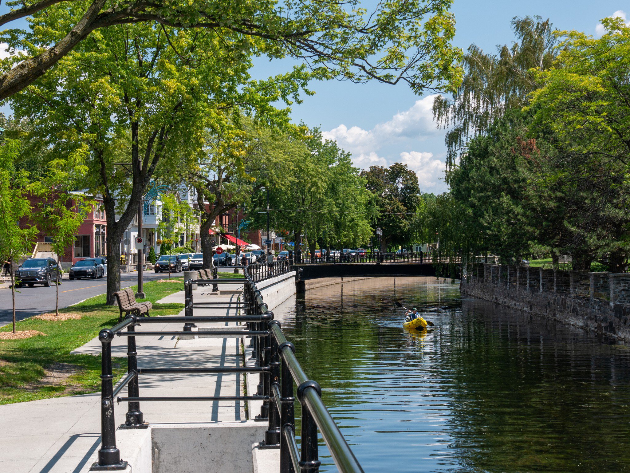 Lachine, Montrel, Canada. July 2021. Man kayaking in the Lachine canal water scenic view of environmental friendly suburbia rich in green trees