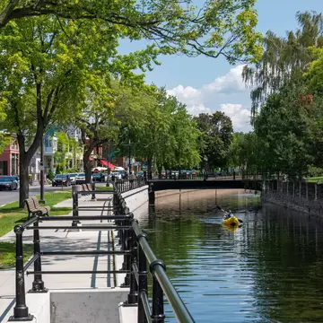 Lachine, Montrel, Canada. July 2021. Man kayaking in the Lachine canal water scenic view of environmental friendly suburbia rich in green trees