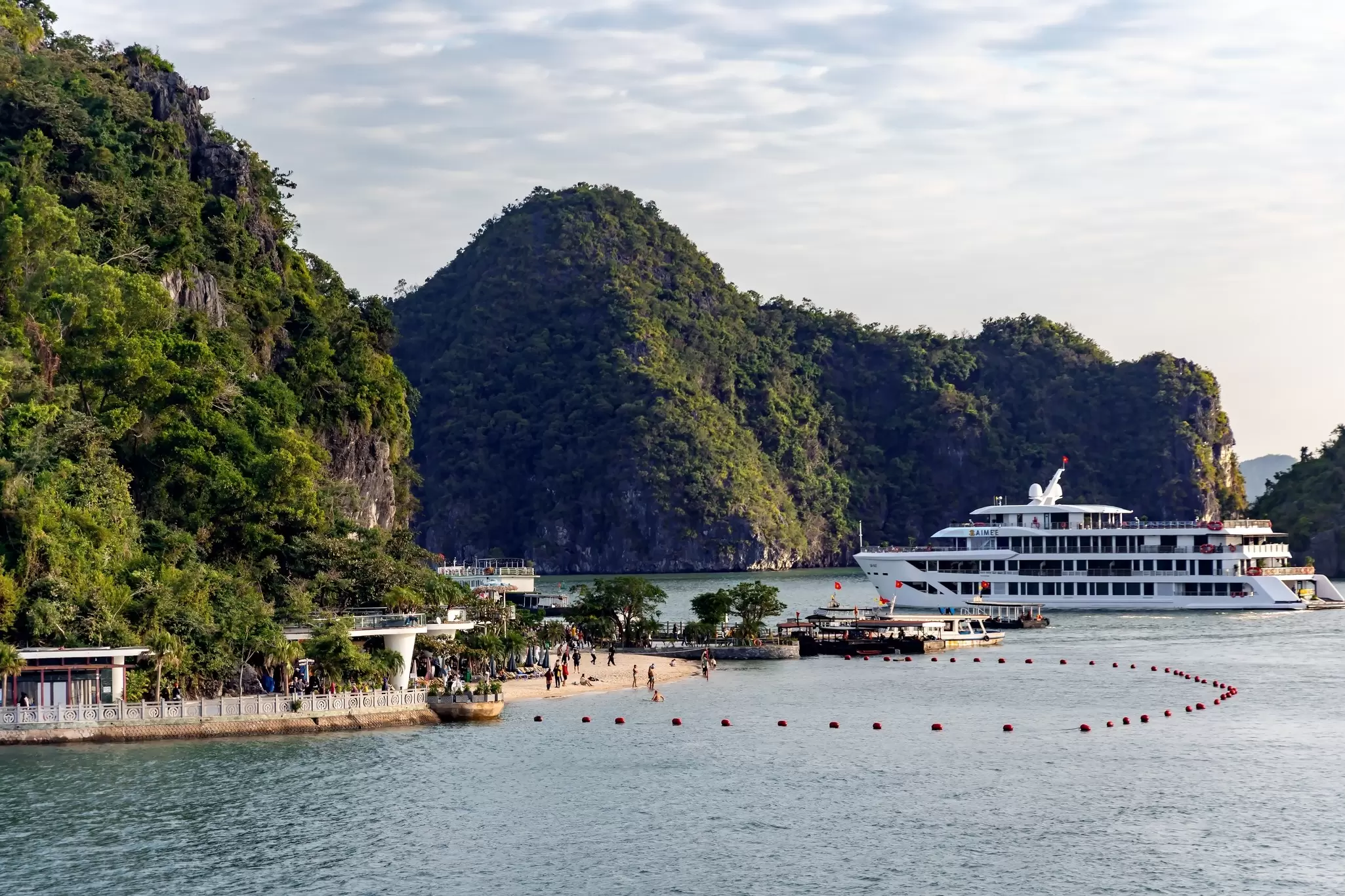 A luxury boat moored near an island beach in Halong Bay, Vietnan, taken from a distance with limestone islands in view