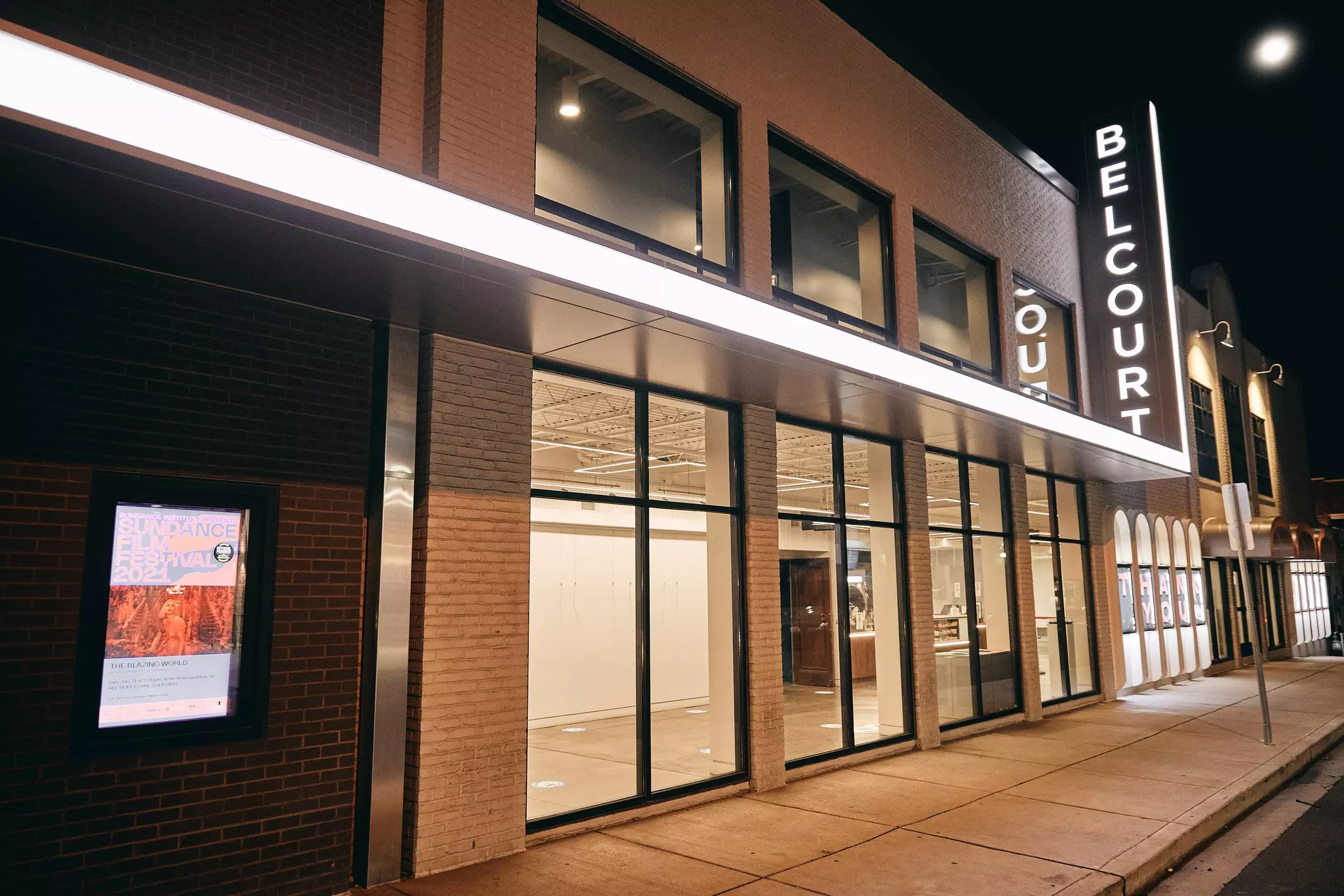 The exterior of a nonprofit film center by night, with a large illuminated sign.