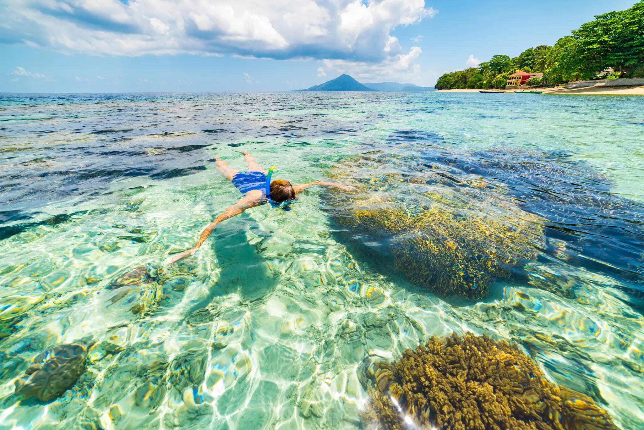 Woman snorkeling in turquoise water on a coral reef in the Banda Islands, Indonesia.