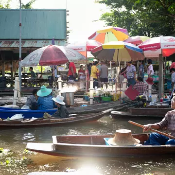 A resident of Tha Kha rows her boat past Tha Kha Floating Market early in the morning. Athikhom Saengchai for Lonely Planet