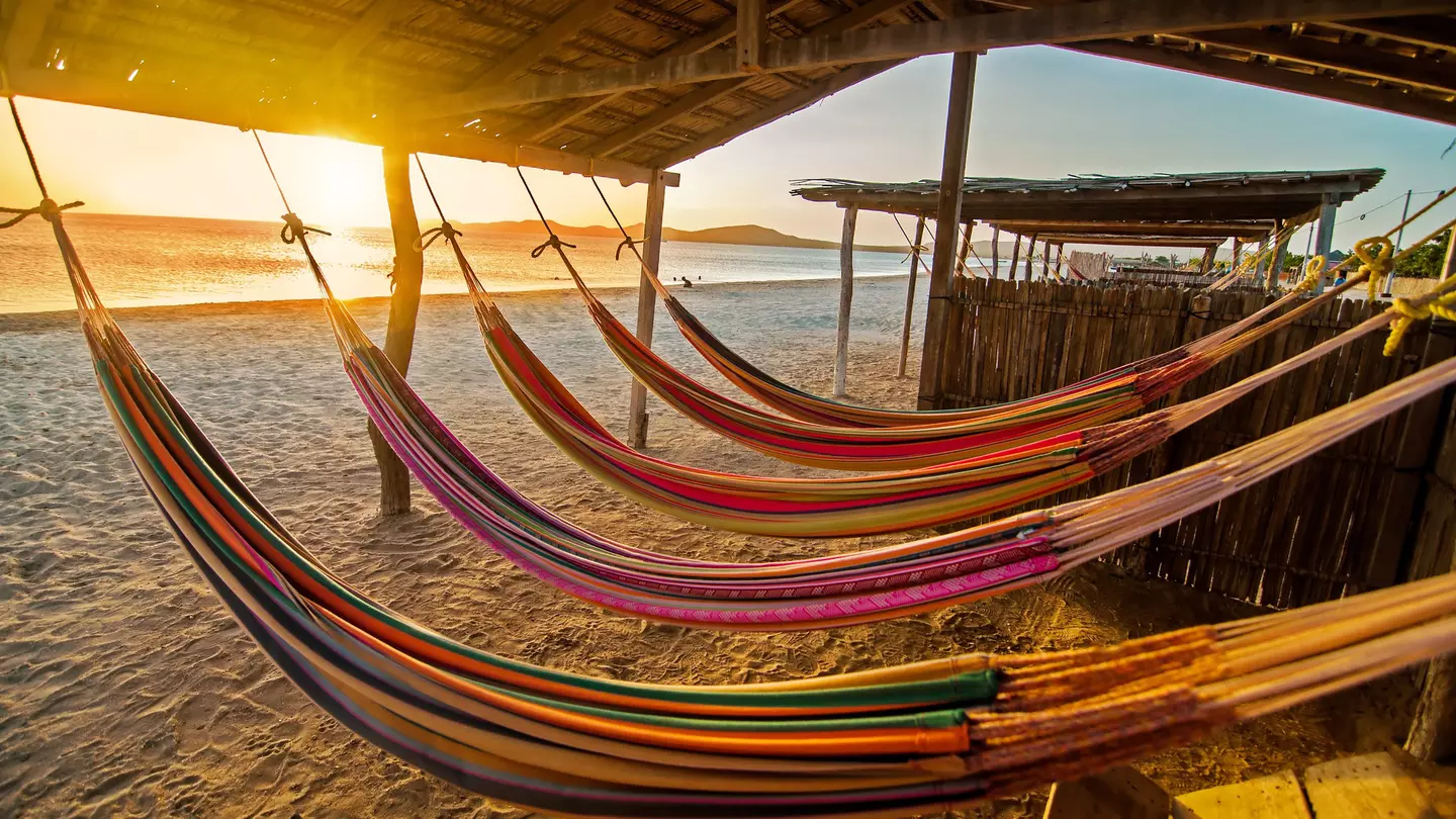 Hammocks on a beach at sunset. DC_Colombia / Getty Images