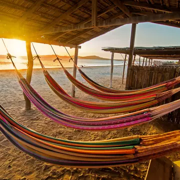 Hammocks on a beach at sunset. DC_Colombia / Getty Images